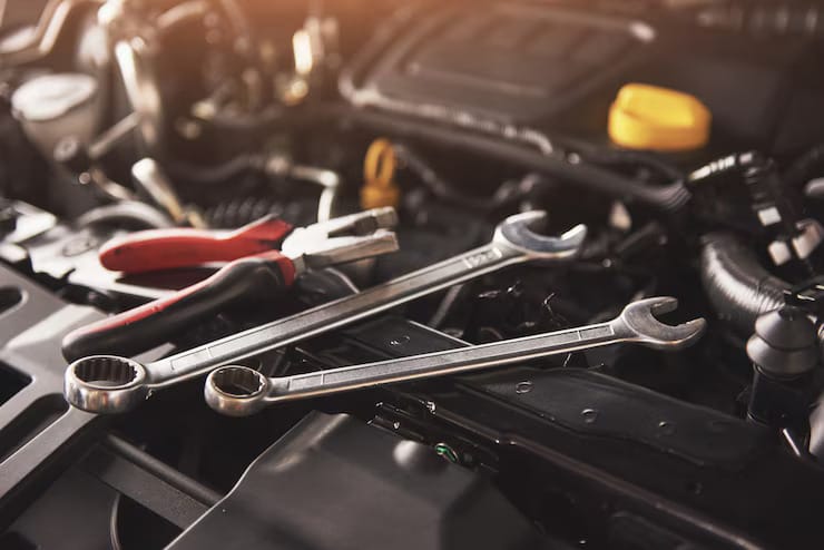 A car engine with wrenches and tools placed on top, indicating maintenance or repair work in progress.